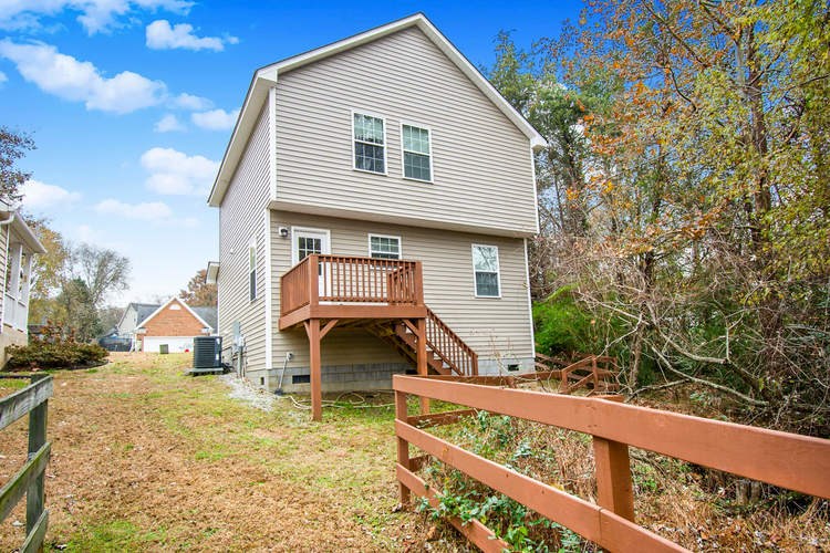 A house with a deck and a fence in front of it.