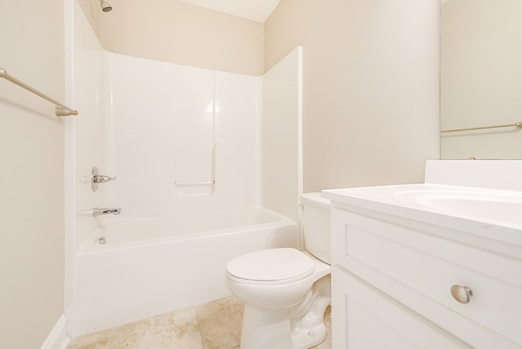 A white bathroom with a toilet, tub, and sink.