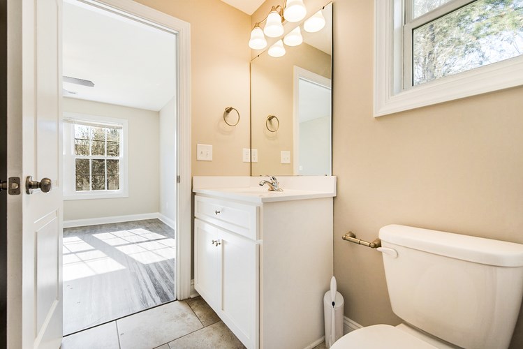 A white bathroom with a tub, sink, and mirror.