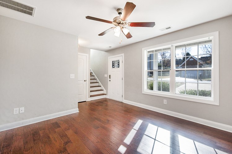A room with a ceiling fan and wooden floors.