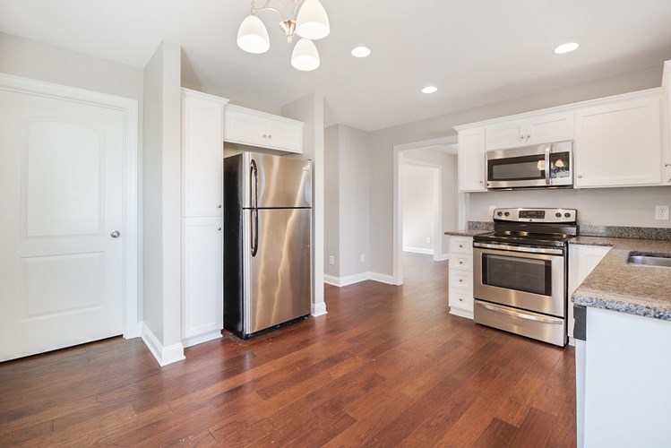 A kitchen with a refrigerator, oven, and microwave.