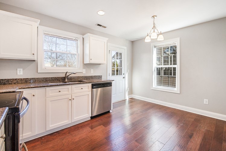A kitchen with white cabinets and a wooden floor.