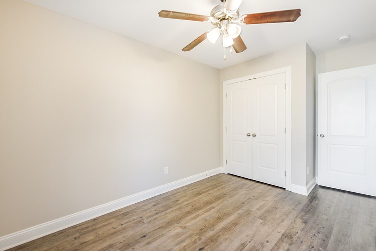 A room with a ceiling fan and wooden floors.