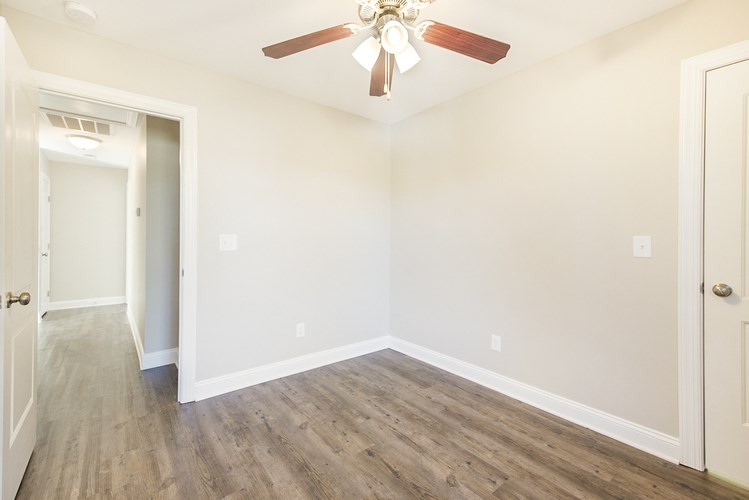 A room with a ceiling fan and wood flooring.