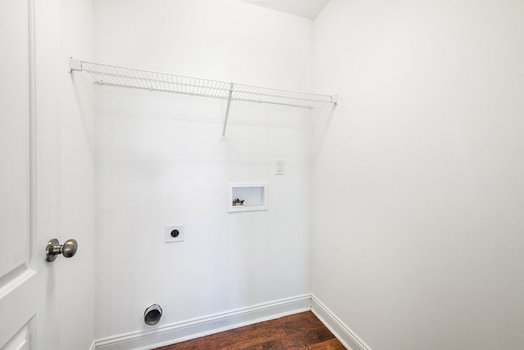A white wall with a shelf and a door.