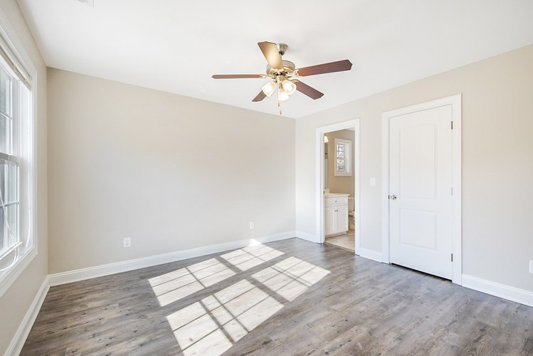 A room with a ceiling fan and a rug on the floor.