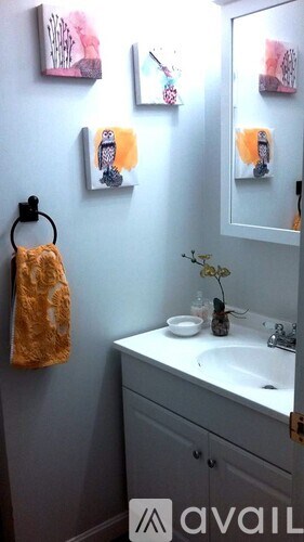 A bathroom with a towel hanging on the wall and a mirror above the sink.
