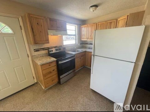 A kitchen with a white refrigerator, wooden cabinets, and a tile backsplash.