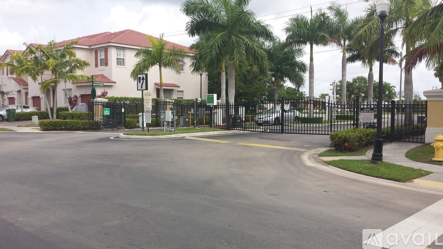 A street view of a gated community with palm trees and a fire hydrant.