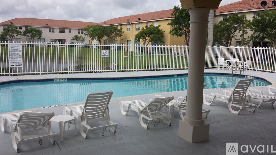 A pool with chairs around it and a sign on the fence.