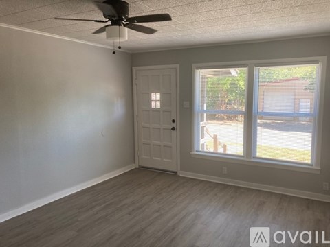 A room with a ceiling fan and a door leading to a balcony.