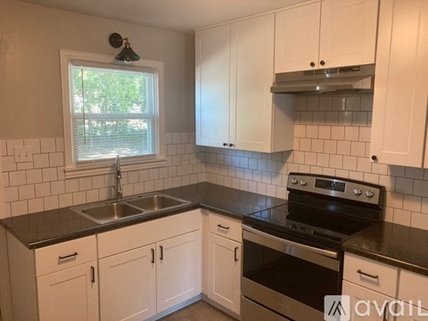 A kitchen with white cabinets and black countertops.