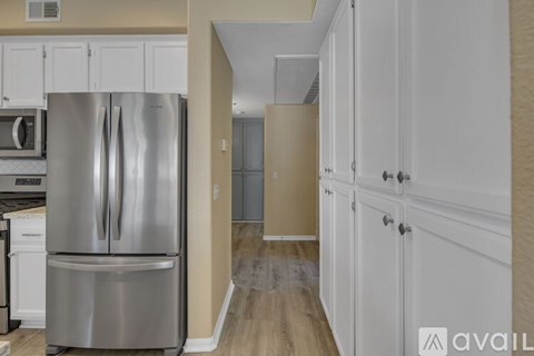 A kitchen with a stainless steel refrigerator and white cabinets.