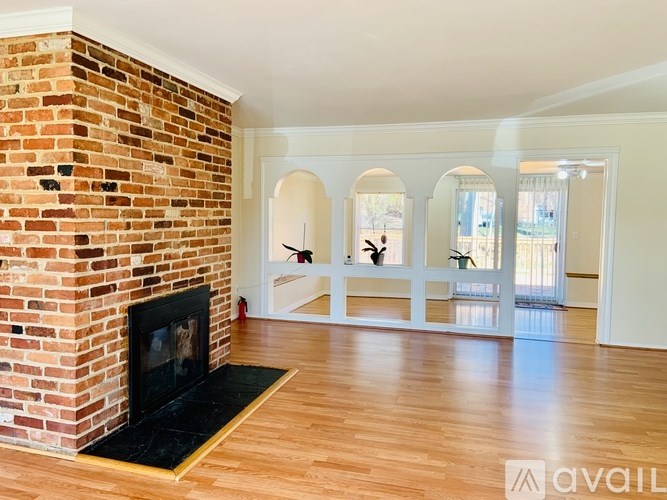 A room with a brick fireplace and wooden floors.