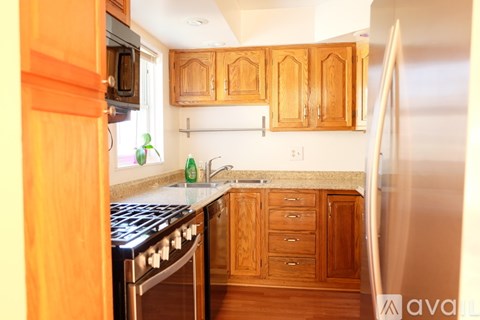 A kitchen with wooden cabinets and a stainless steel refrigerator.
