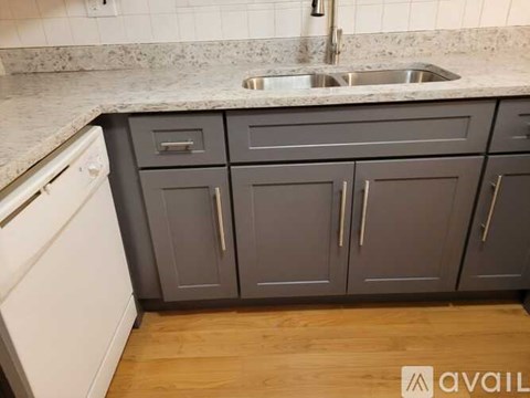 A kitchen with grey cabinets and a white dishwasher.