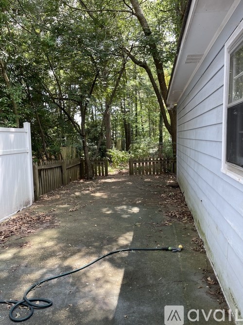 A white house with a green hose laying on the ground.