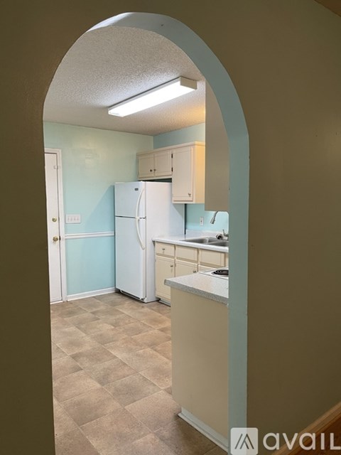 A kitchen with a white refrigerator and a checkered floor.