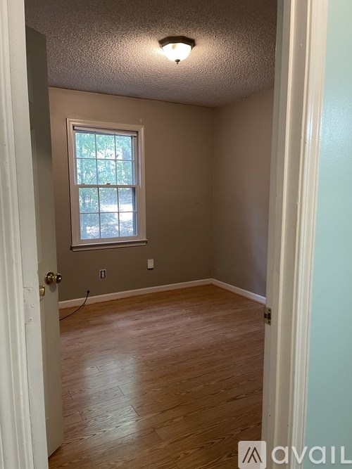 A room with a window and wooden floors.