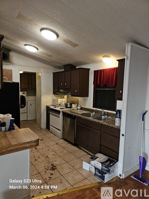 A kitchen with brown cabinets and a black fridge.