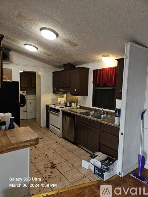 A kitchen with brown cabinets and a black fridge.