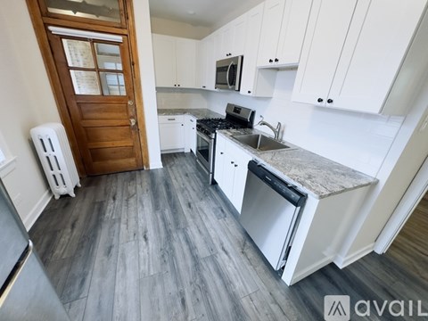 A kitchen with white cabinets and a wooden door.