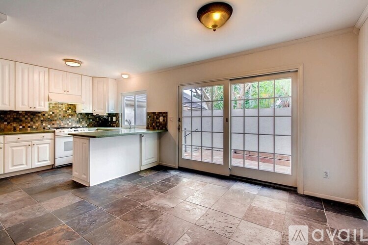 A kitchen with a tiled floor and a large window.
