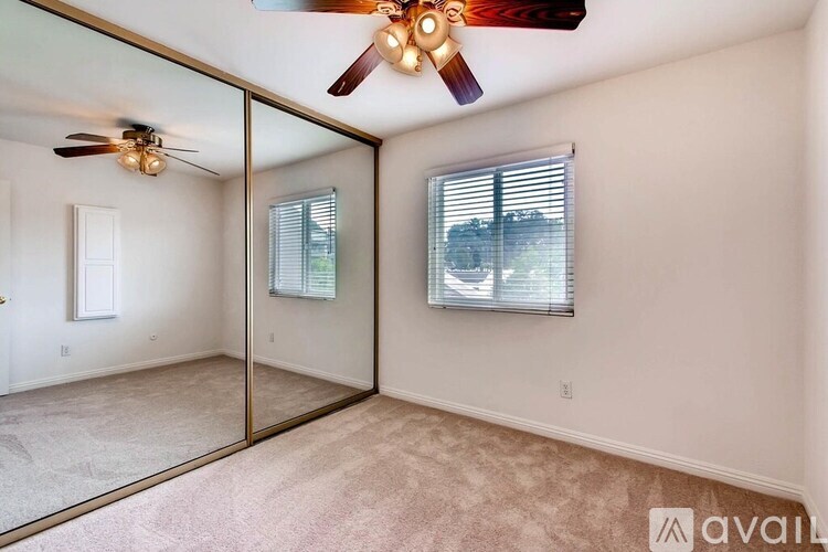 A room with a ceiling fan and a mirrored wall.