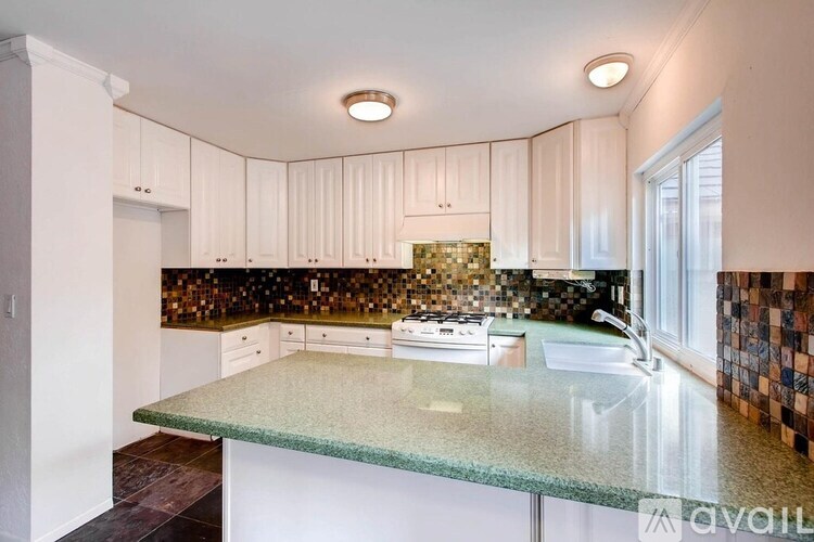 A kitchen with a granite countertop and white cabinets.