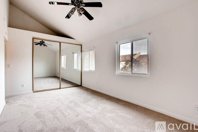 A room with a ceiling fan and a large mirror on the wall.