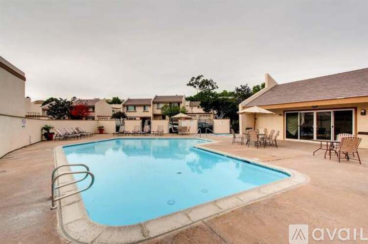 A swimming pool in a backyard with a slide and chairs around it.
