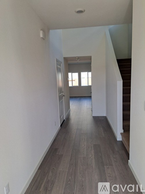 A long hallway with wood floors and white walls.