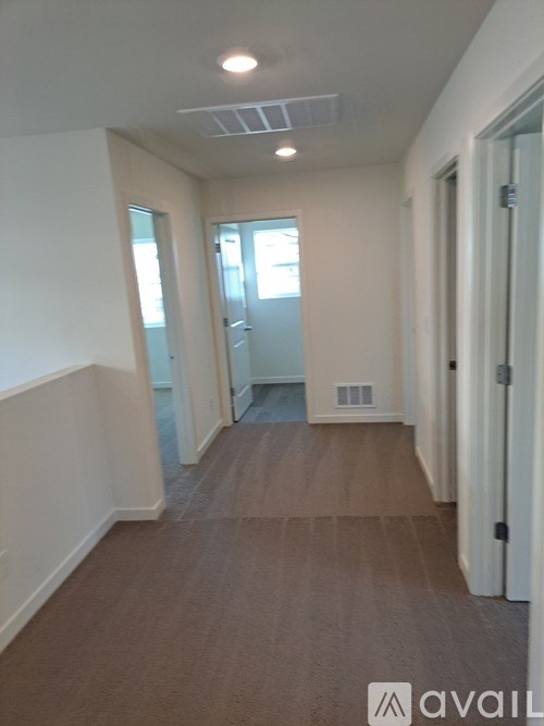 A hallway with a carpeted floor and white walls.