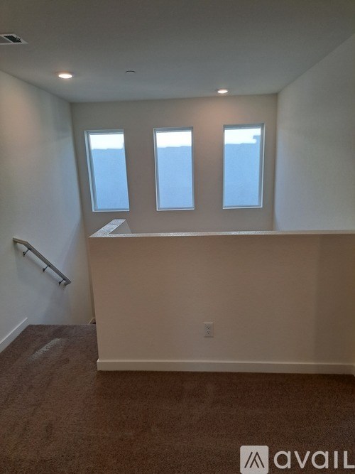 A room with a carpeted floor and three windows.
