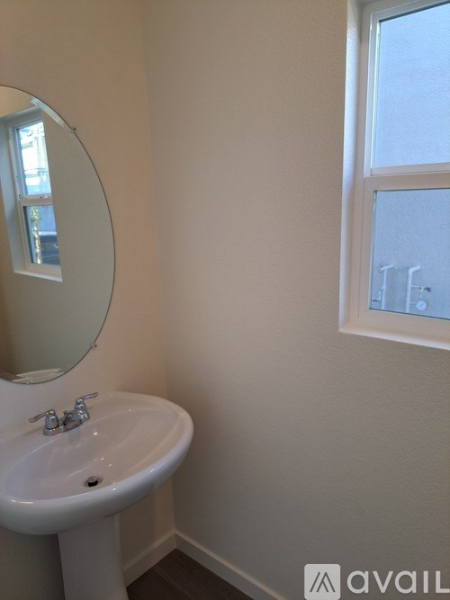 A white sink with a round mirror above it.