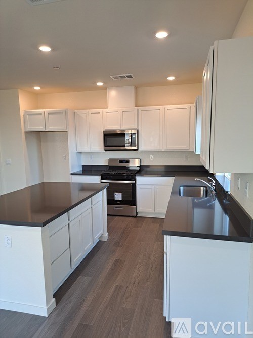 A kitchen with white cabinets and a black countertop.