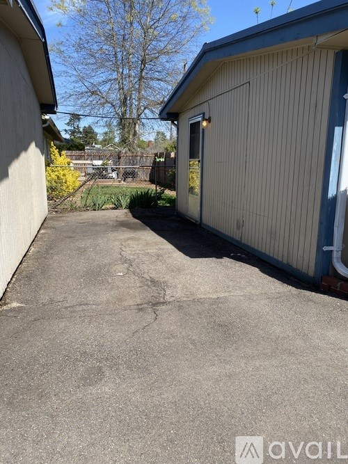 A concrete driveway leads to a building with a blue trim.