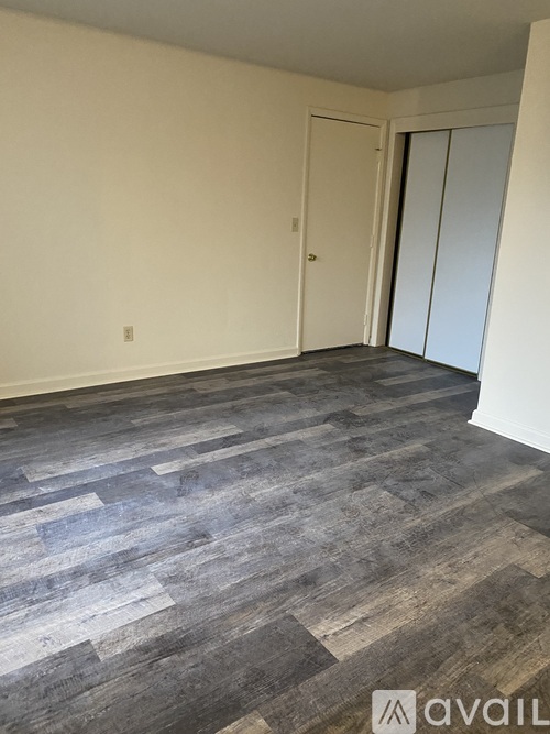 A room with a grey wood floor and white walls.