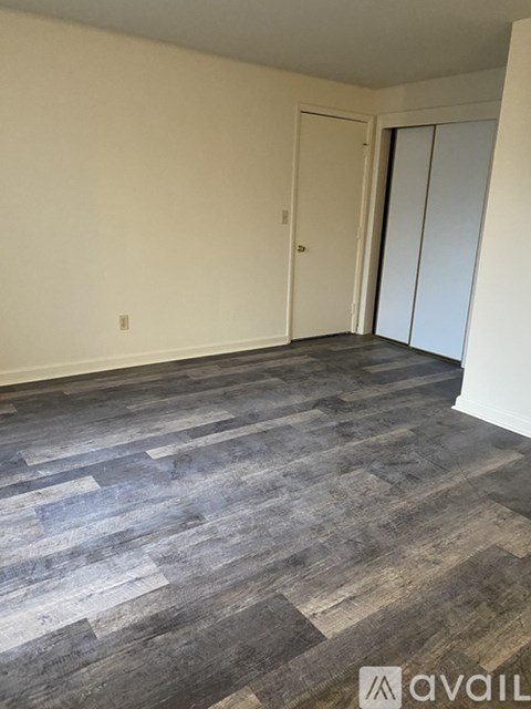 A room with a grey wood floor and white walls.