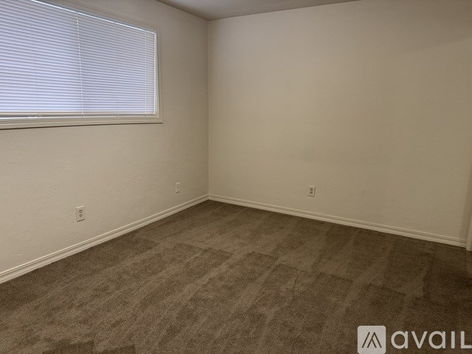 A room with a carpeted floor and a window with blinds.