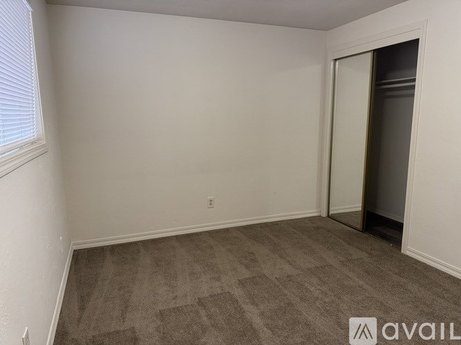 A room with a carpeted floor and a door leading to another room.