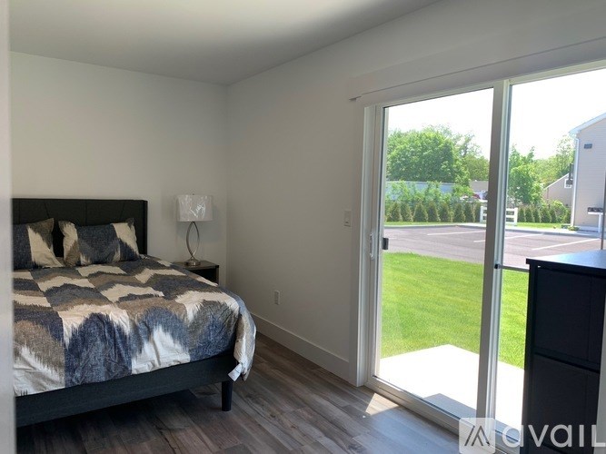 A bedroom with a bed, nightstand, and sliding glass doors.