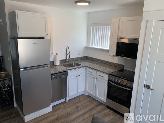 A kitchen with a refrigerator, microwave, oven, and sink.
