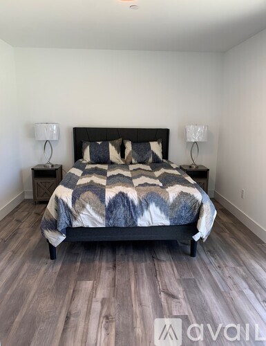 A bedroom with a bed, two lamps, and a patterned bedspread.