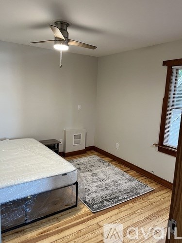 A bedroom with a bed, rug, and ceiling fan.