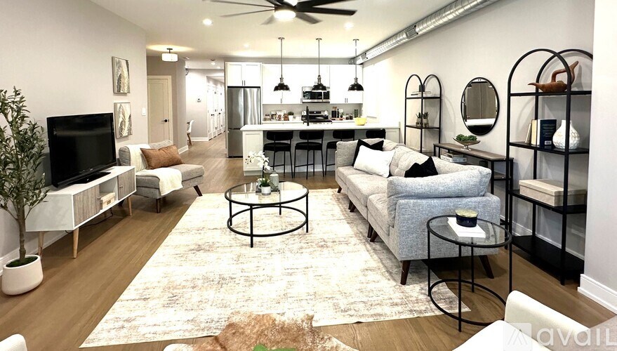 A well-lit, modern living room with a television, sofas, and a dining area.