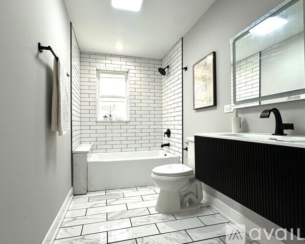 A white toilet sits in a bathroom with a black and white tiled floor.