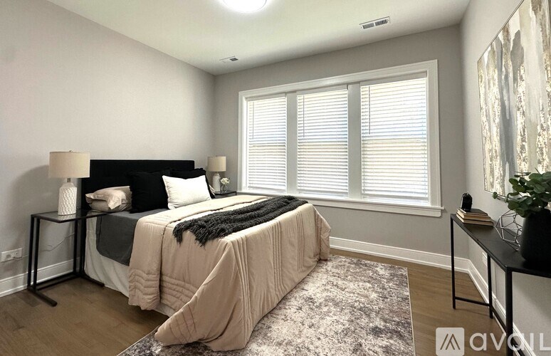 A bedroom with a bed, nightstand, and window with blinds.