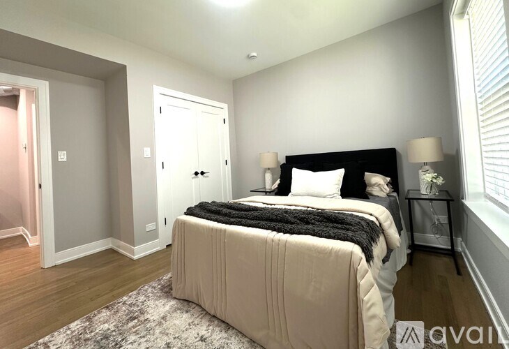 A bedroom with a large bed and a window with blinds.