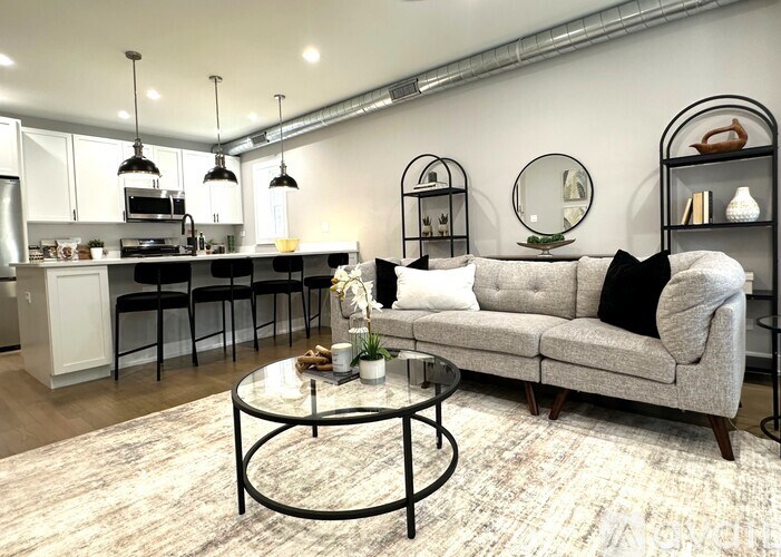 A modern living room with a grey couch and a glass coffee table.